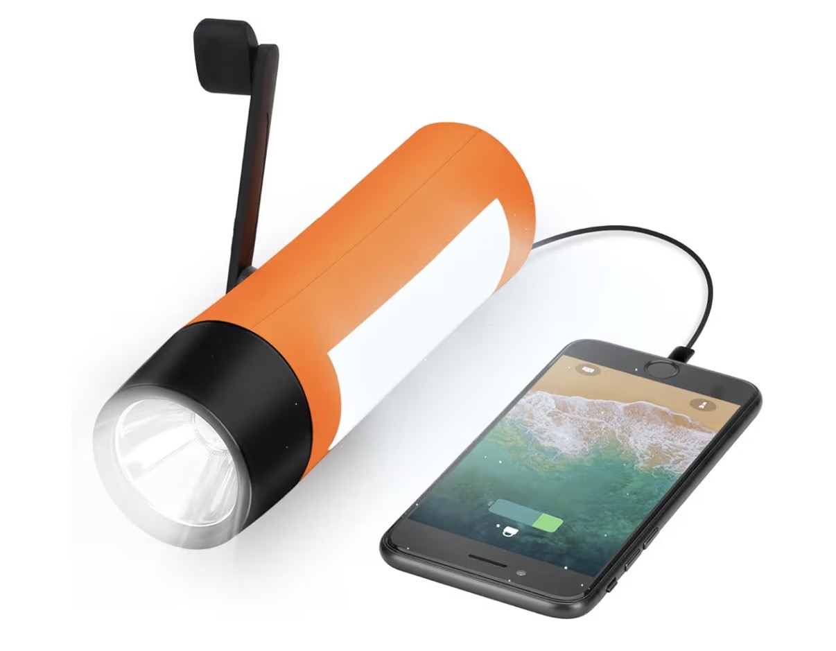 Orange hand-crank torch with a side lantern panel, charging a phone