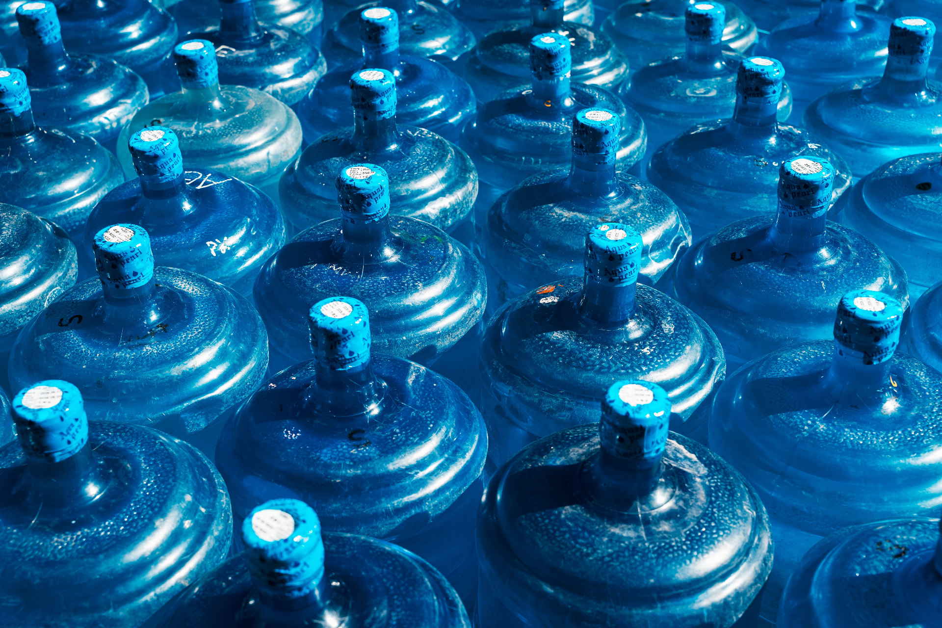 Rows of large blue water cooler bottles stored together